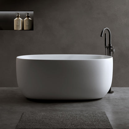 Bañera independiente de piedra de resina de superficie sólida. Diseño moderno con desagüe automático y rebosadero, ideal para hogares pequeños. Blanco mate.